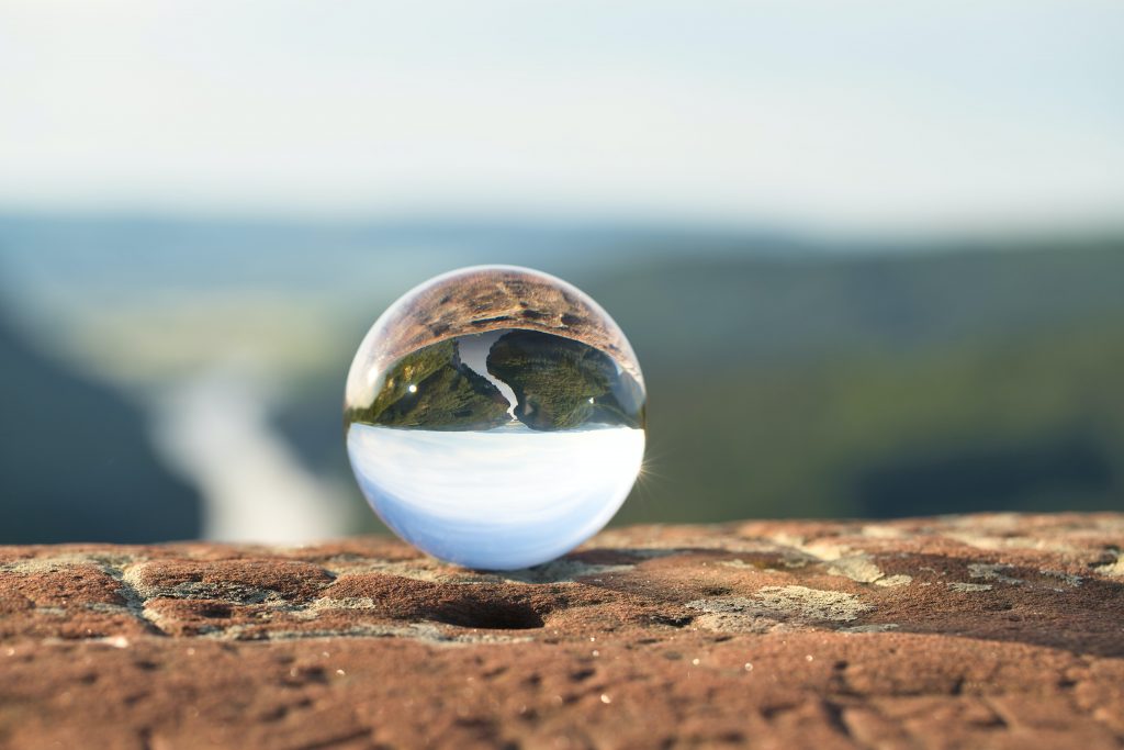 Glass marble showing the reflection of a valley with a river flowing through