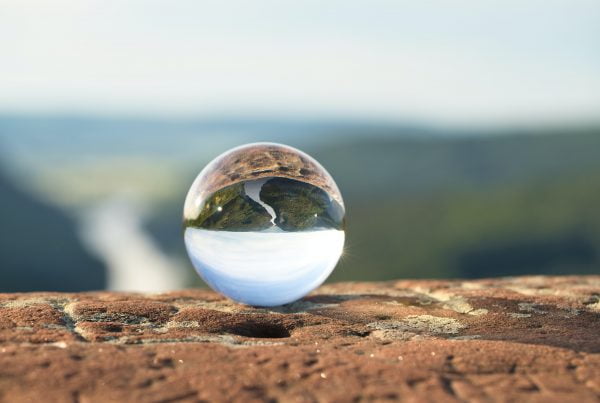Glass marble showing the reflection of a valley with a river flowing through