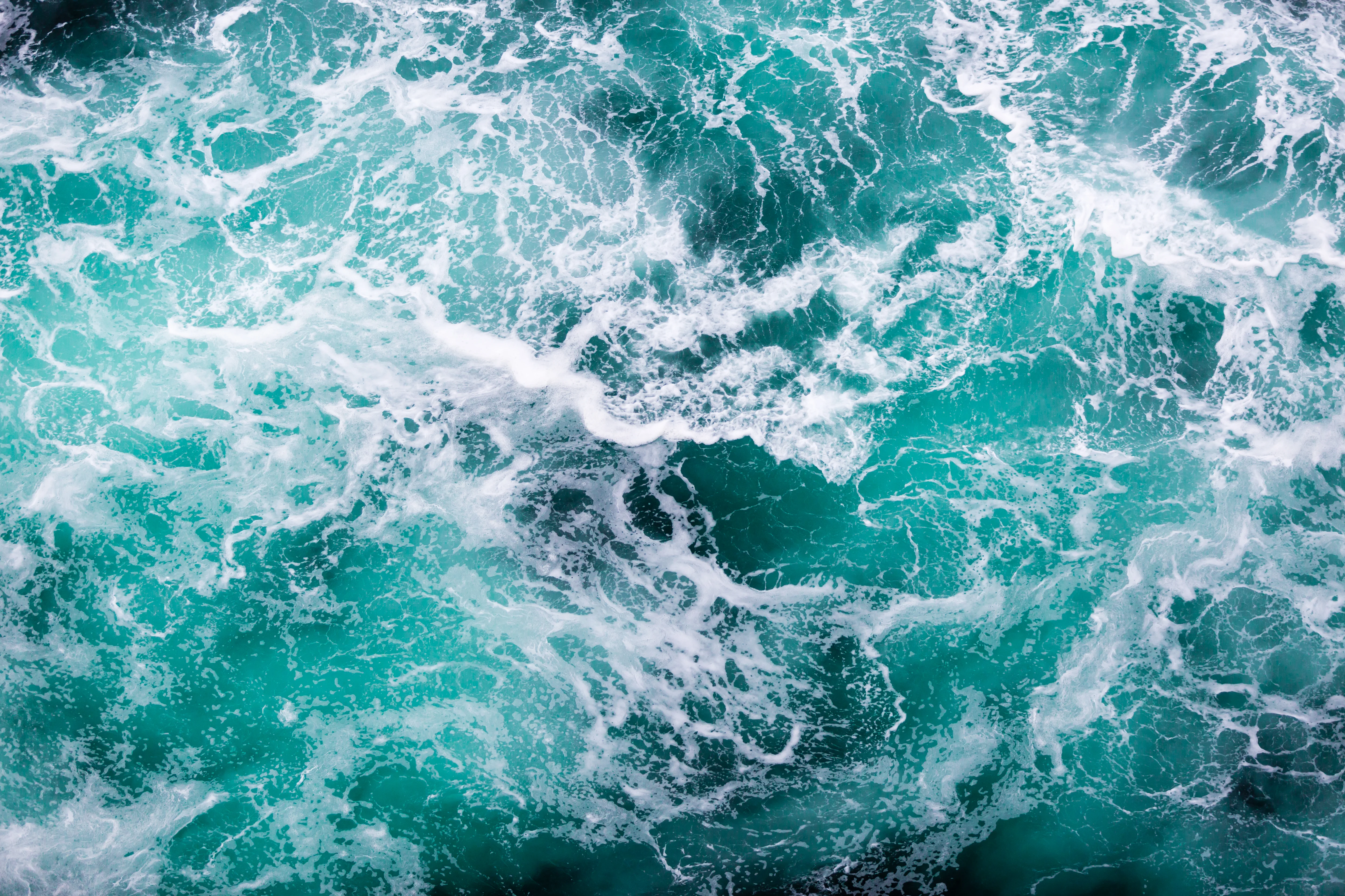 Aqua coloured waves in the water with white sea foam
